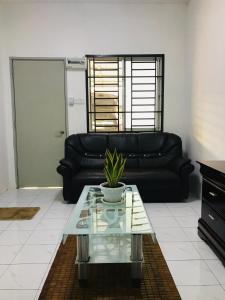 ein Wohnzimmer mit einem schwarzen Sofa und einem Glastisch in der Unterkunft Alyn Home Batu Pahat II Wifi Coway in Kampong Mohamad Noor