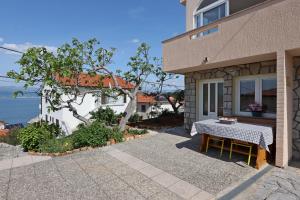 a table sitting outside of a house with a view of the ocean at Apartments and rooms with parking space Vrbnik, Krk - 5299 in Vrbnik