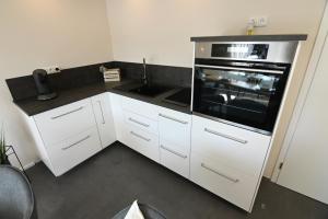 a small kitchen with white cabinets and an oven at Gästehaus Achenbach in Biedenkopf
