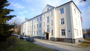 un gran edificio blanco con coches estacionados frente a él en Meta Biblioteka en Puławy