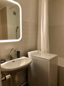 La salle de bains blanche est pourvue d'un lavabo et d'un miroir. dans l'établissement Charmant Studio à 2 pas de la gare, à Lons-le-Saunier