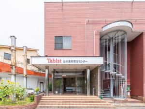 un edificio di mattoni rossi con un cartello che legge il supermercato tikishi di Tabist Izumi Yusen Shukuhaku Center a Izumi