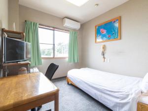 una stanza con un letto, una scrivania e una televisione di Tabist Izumi Yusen Shukuhaku Center a Izumi