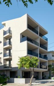 un edificio de apartamentos con un árbol delante de él en Almy Luxury Apartments, en La Canea