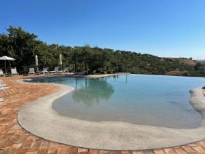 a large swimming pool with chairs and water at Castello di Serragiumenta in Firmo