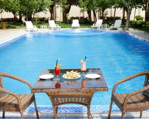 un tavolo e sedie accanto alla piscina di Asmald Palace Hotel a Qo‘qon