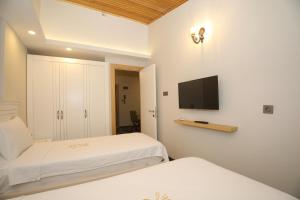 a bedroom with two beds and a flat screen tv at Raymar Hotels Muğla in Mugla