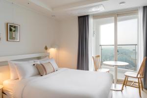 um quarto com uma cama branca e uma grande janela em Urbanstay Sokcho Deungdae Beach em Sokcho