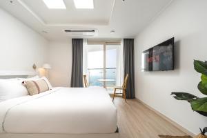 a white bedroom with a bed and a table at Urbanstay Sokcho Deungdae Beach in Sokcho