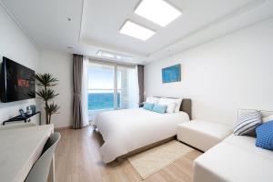 Urbanstay Sokcho Deungdae Beach في سوكشو: غرفة نوم بيضاء مع سرير وأريكة