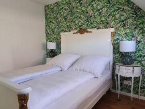 Cama blanca en habitación con pared verde en Gästehaus - Im Gärtle II en Niederrotweil