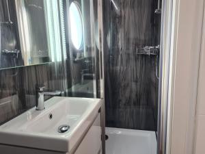 a white bathroom with a sink and a shower at Hausboot La Mare Emma in Weyhe