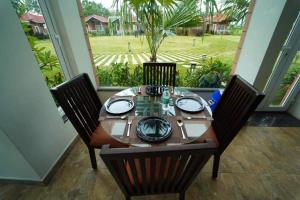 stół z 4 krzesłami i duże okno w obiekcie vihangama Home Stay w mieście Chāmundi