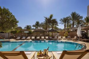 uma piscina num resort com cadeiras e uma mesa em Play Eilat Hotel em Eilat