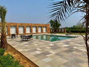 a swimming pool with tables and chairs next to a building at Sariska Safari Lodge in Thāna Ghāzi