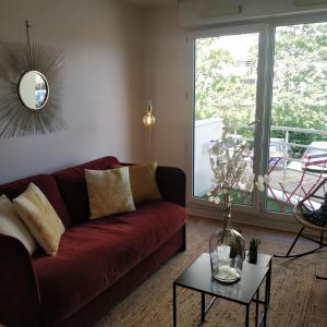 a living room with a red couch and a table at Direct Aéroport et centre historique de Bordeaux in Mérignac