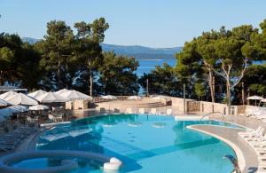 a swimming pool with chairs and a view of the water at Bluesun Hotel Elaphusa in Bol