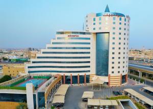 - un grand bâtiment blanc avec une piscine en face dans l'établissement Mövenpick Hotel Qassim, à Buraydah