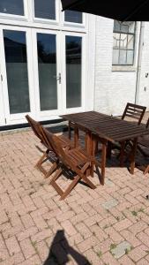 een houten picknicktafel en stoelen op een bakstenen patio bij Authentieke studio in hartje Joure in Joure