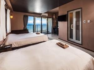 two beds in a room with a view of the ocean at Hotel Sunset American in Chatan
