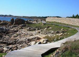 un chemin à côté d'une rivière avec des rochers et un mur dans l'établissement Vistamar Galicia Rua Muralla, à Ribeira