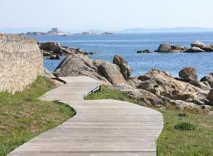 un chemin en bois menant à l'océan avec des rochers dans l'établissement Vistamar Galicia Rua Muralla, à Ribeira