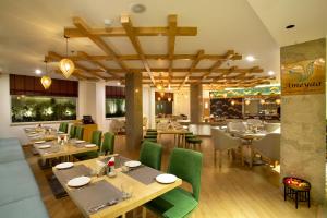 un restaurant avec des tables en bois et des chaises vertes dans l'établissement Ramada by Wyndham Katra Station Road, à Katra