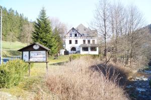 ein großes weißes Haus mit einem Schild davor in der Unterkunft Gasthof und Pension Hammerschänke in Wildenthal