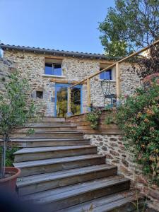 eine Holztreppe, die zu einem Steinhaus führt in der Unterkunft La maison du vigneron in Auzon