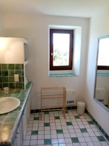 een badkamer met een wastafel, een raam en een spiegel bij Le Lavoir in Lacoste