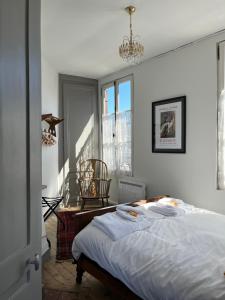 a bedroom with a bed and a chair and a window at Maison de la Calonne - Riverside house & terrace in Cormeilles
