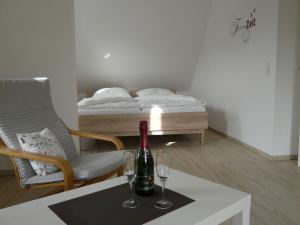 Marienfelde的住宿－Das Haus am See，一间设有一张桌子、一瓶葡萄酒和一张床的客房