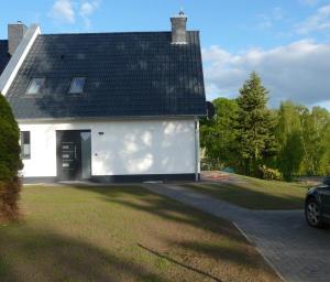 una casa blanca con techo negro en Das Haus am See en Marienfelde