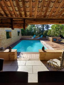a swimming pool with chairs and a wooden roof at LODGES EN PIERRES DOREES in Saint-Germain-Nuelles