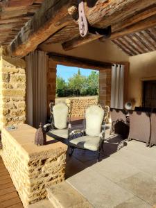 d'une terrasse avec 2 chaises et un mur en pierre. dans l'établissement LODGES EN PIERRES DOREES, à Saint-Germain-Nuelles