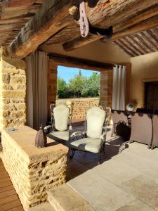 a patio with two chairs and a stone wall at LODGES EN PIERRES DOREES in Saint-Germain-Nuelles