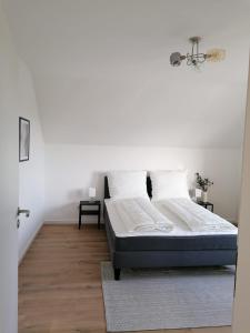 a bedroom with a bed and a white wall at EIFELSTERN-Schöne Ferienwohnung mit Balkon in Kalenborn-Scheuern