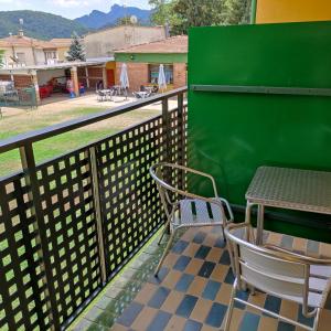 una mesa y sillas en un balcón con una pared verde en Alberg Restaurant Bellavista, en Santa Pau