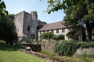 an old stone building with a tower in a yard at The Bothy Beverston Castle in Tetbury