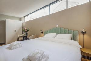 1 dormitorio con 1 cama blanca grande y toallas. en Bens The Walton, en Ámsterdam