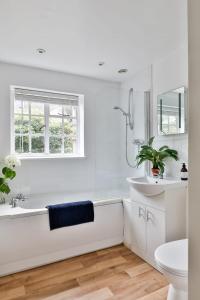 a white bathroom with a tub and a sink at The Butlers Bungalow Beverston Castle in Tetbury