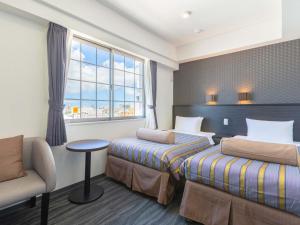 a hotel room with two beds and a chair and a window at Hotel Koza in Okinawa City