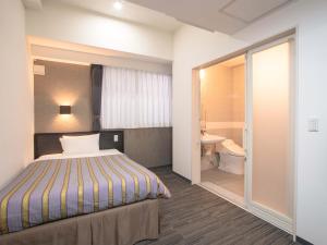 a hotel room with a bed and a bathroom at Hotel Koza in Okinawa City