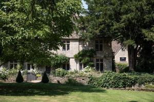 an old stone house with trees and a yard at The Butlers Bungalow Beverston Castle in Tetbury