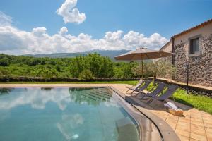 una piscina con 2 sillas y una sombrilla en Villa Terre Normanne 16, Emma Villas en Castiglione di Sicilia