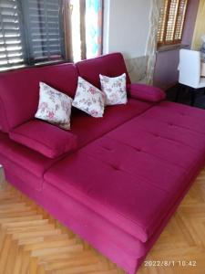 Un sofá púrpura con cuatro almohadas. en Apartments Ribić, en Umag