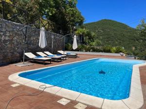 a swimming pool with chairs and umbrellas in a house at Villa Belvedere Relax,Piscina privata e Privacy in Alassio