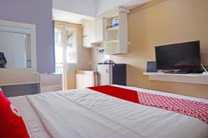 Schlafzimmer mit einem roten und weißen Bett und einem TV in der Unterkunft Collection O GLV Tower B in Tangerang