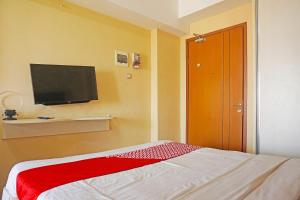 um quarto com uma cama e uma televisão de ecrã plano em Collection O GLV Tower B em Tangerang