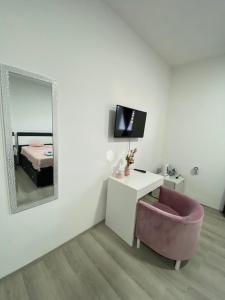 a living room with a mirror and a pink chair at Apartmani Home in Zaječar